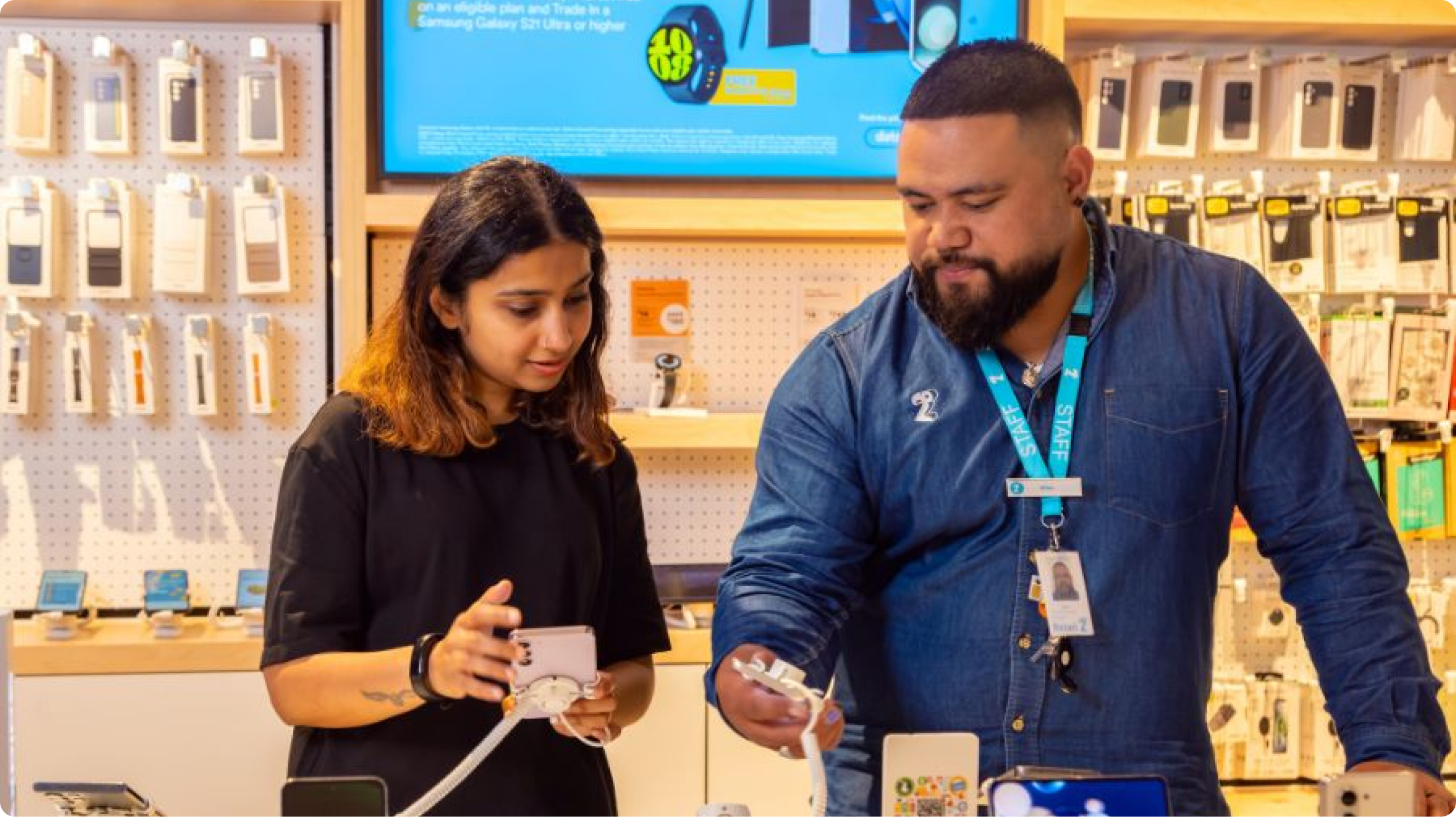 Image of a retail staff member assisting a customer with a phone