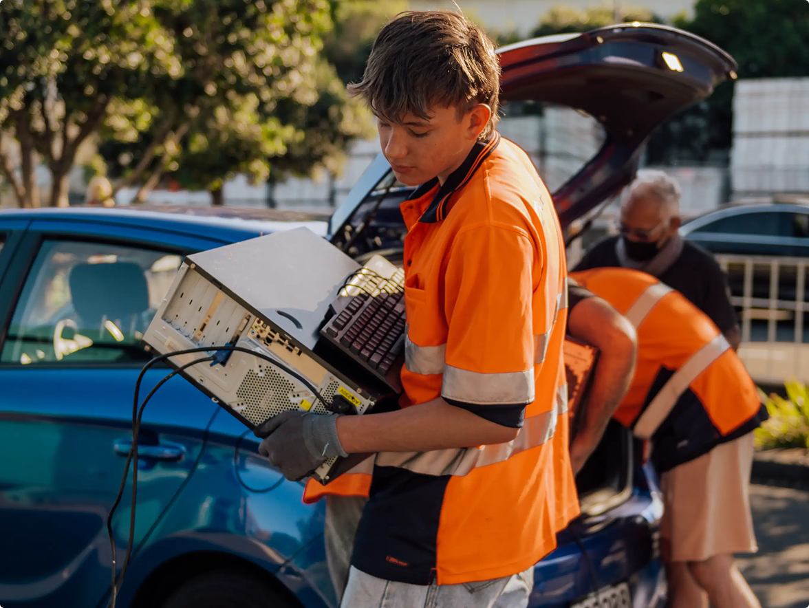 Young man carrying a computer tower and computer keyboard