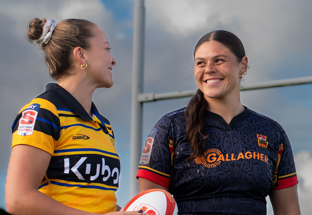 two female rugby players smiling at each other