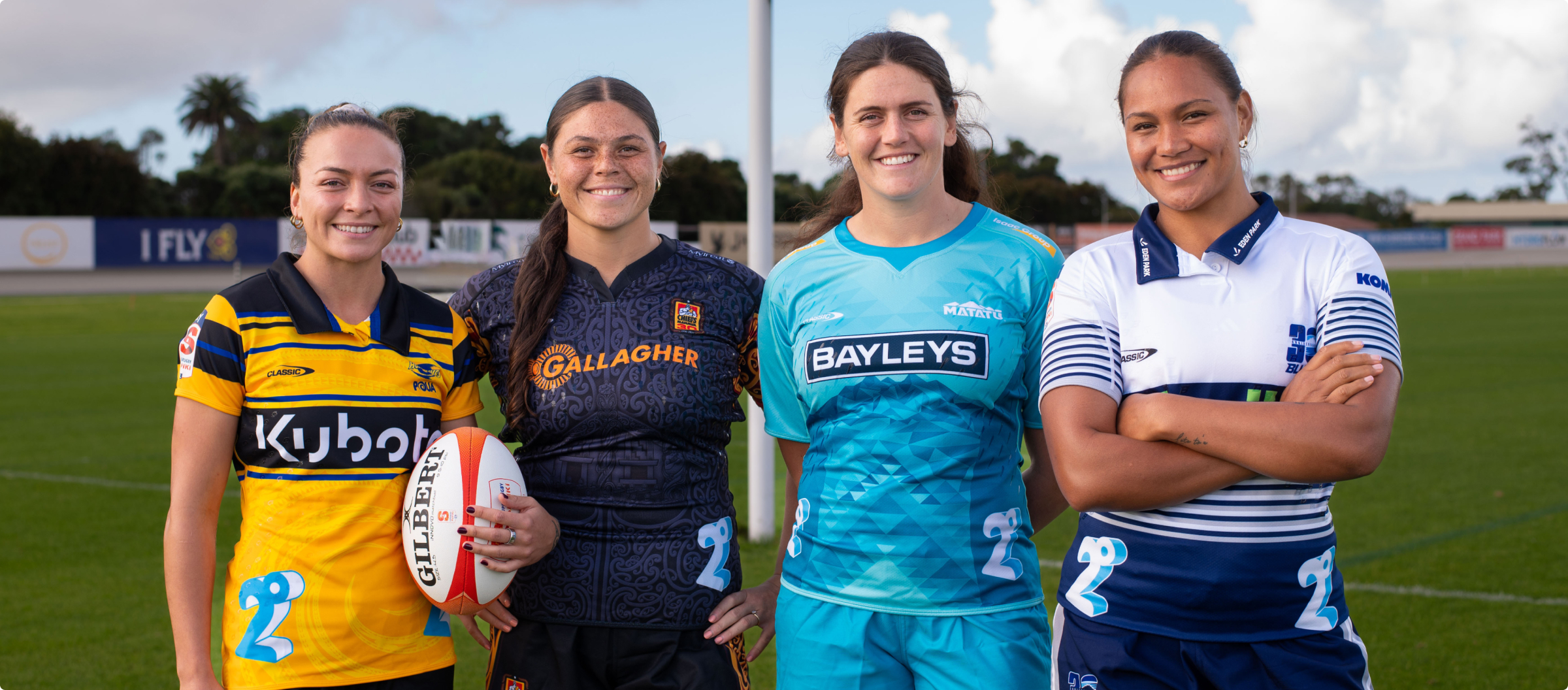 photo of four female rubgy players standing on the field together