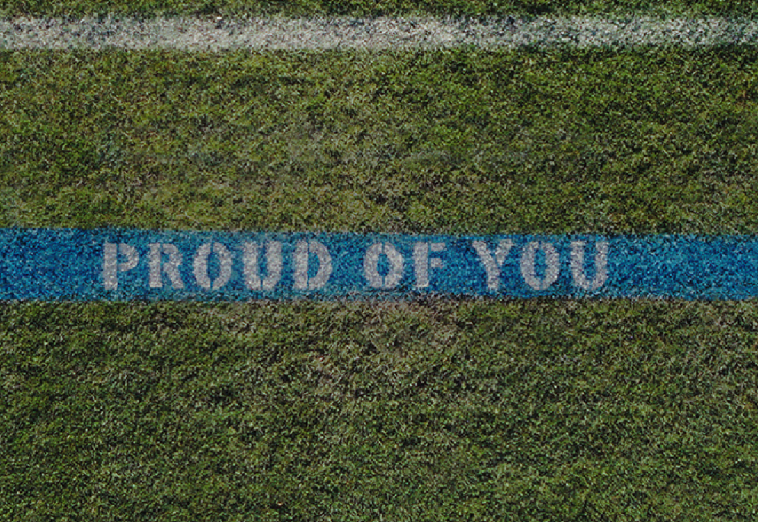 Photo of the blue sideline on a field with the words "Proud of You"
