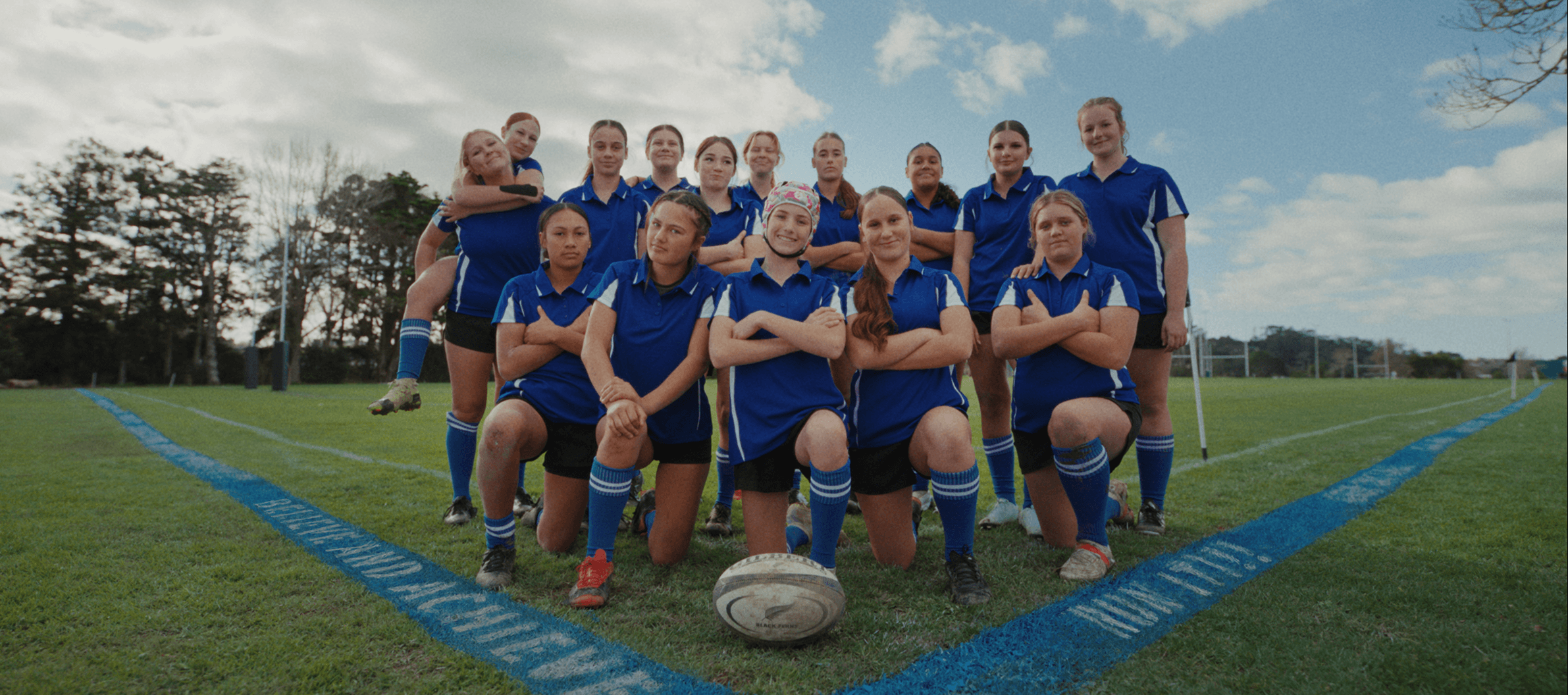 Image of a girls rugby team with the blue SupportHER Line
