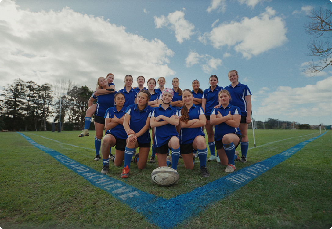 Photo of a girls rugby team beside the blue sideline