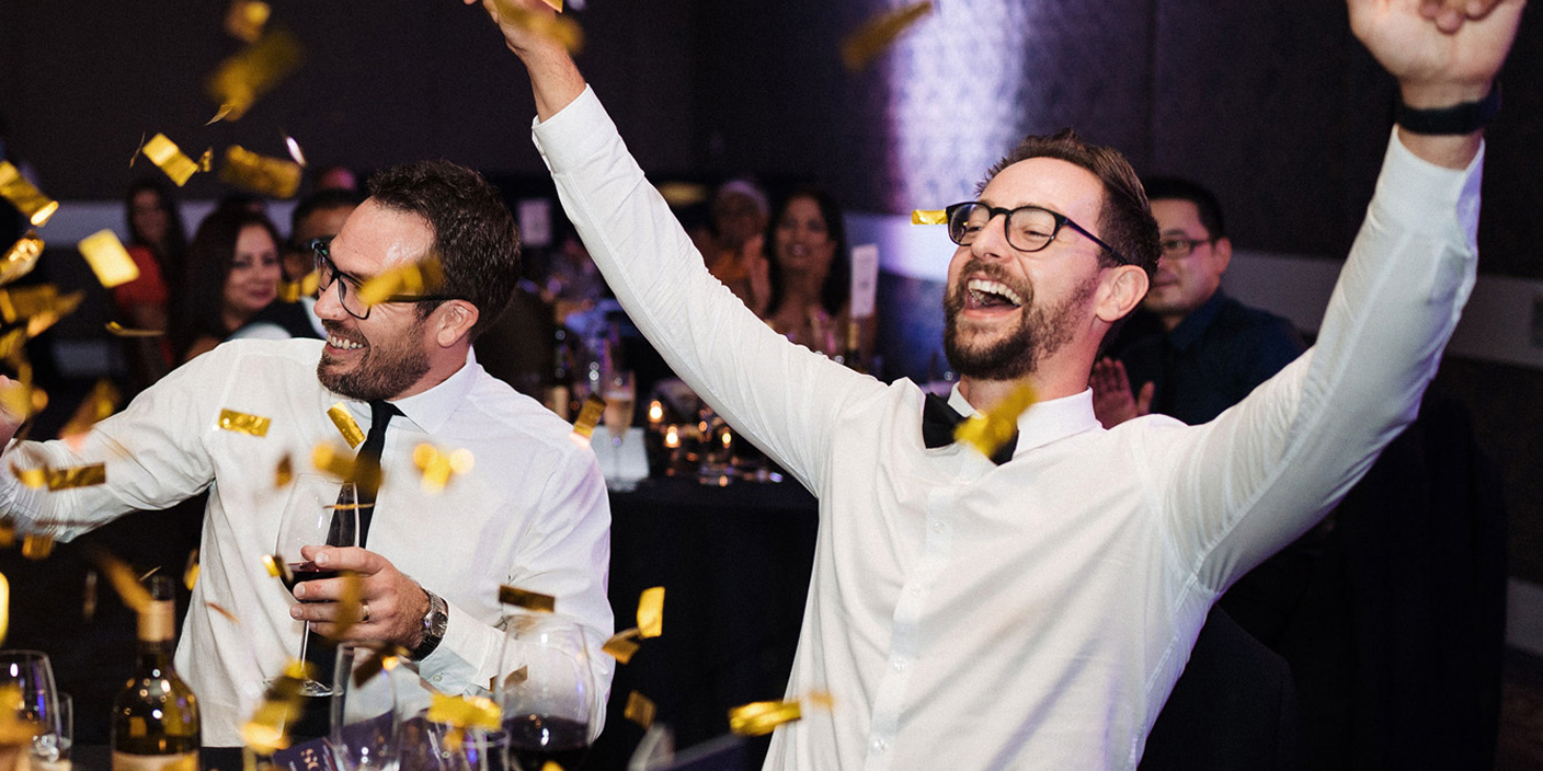 Two men celebrating a award win with confetti falling around them