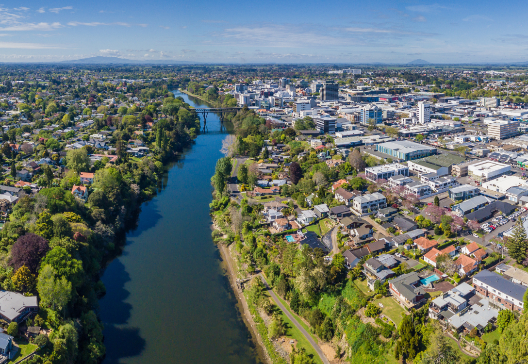 Photo of a river flowing through a city with trees and buildings on either side