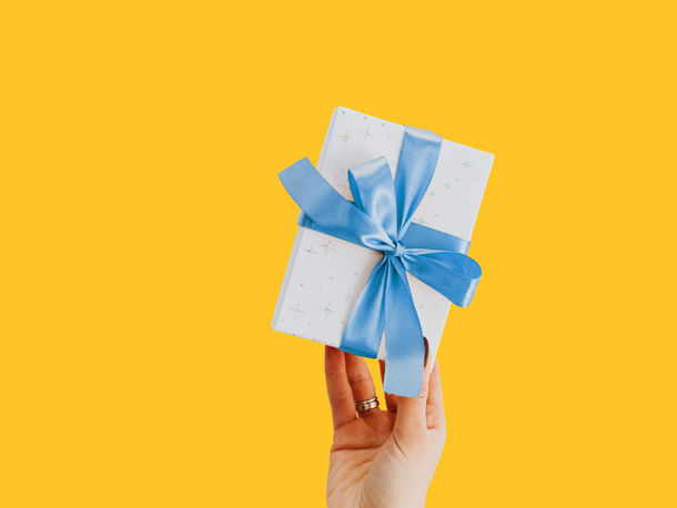 hand holding a wrapped present on a yellow background