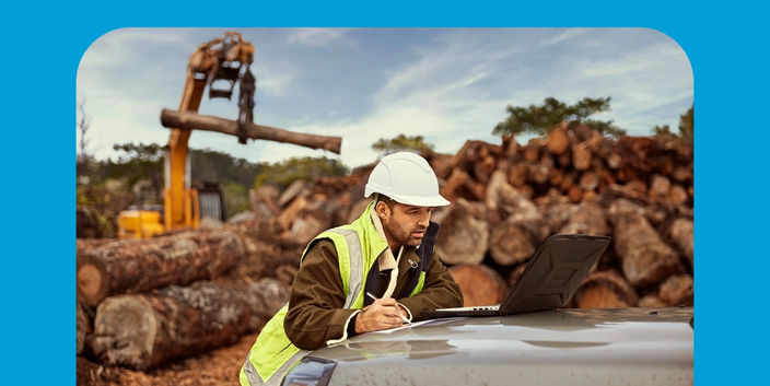 construction worker leaning against the bonnet of his car looking at plans